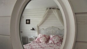 Ein Schlafzimmer mit Baldachinbett, Nachttisch, Lampe und Wanduhr.