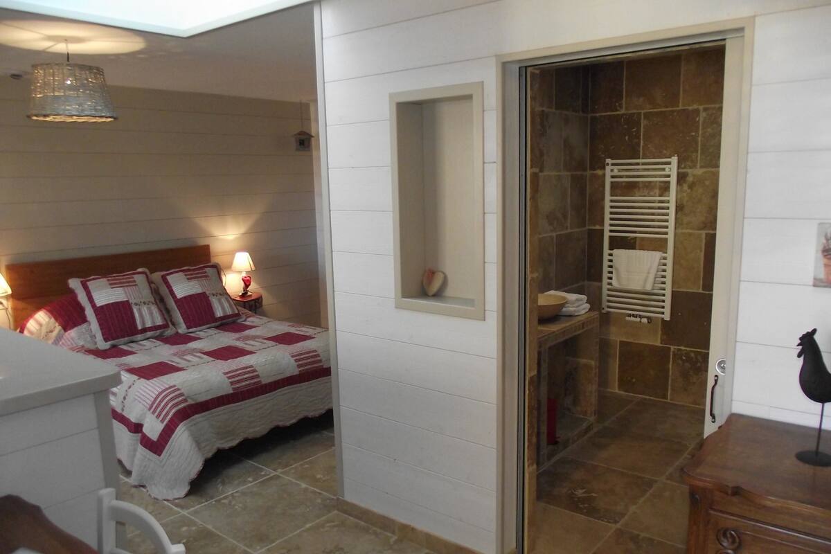 Une chambre à coucher avec un lit, une table de chevet, une lampe et une petite fenêtre.