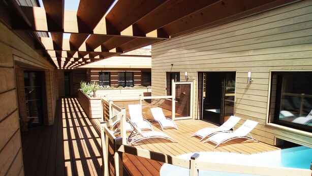 Eine Holzterrasse mit Liegestühlen und einem Pool.