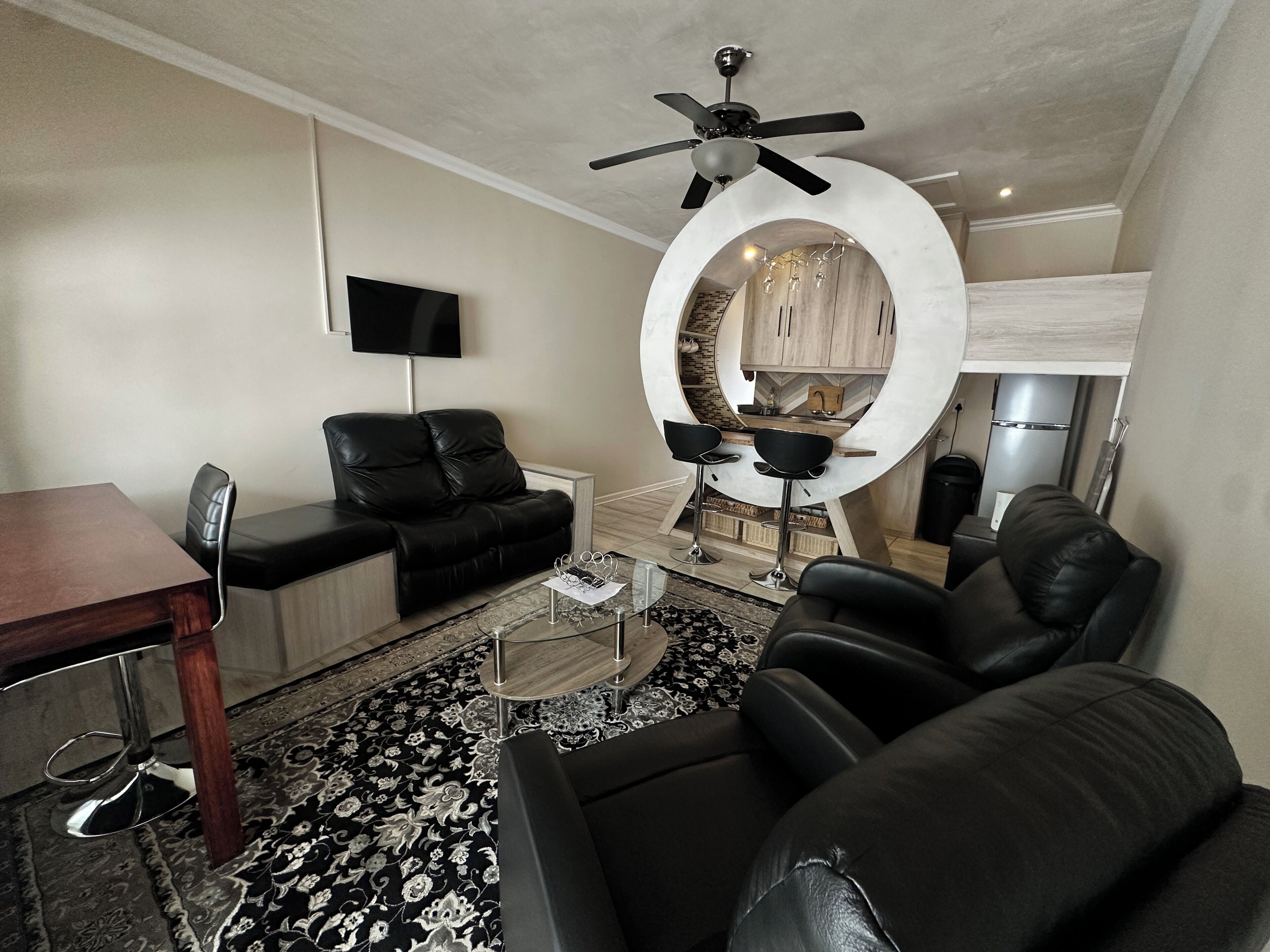 A modern living room with a sofa, chairs, a coffee table, and a TV.