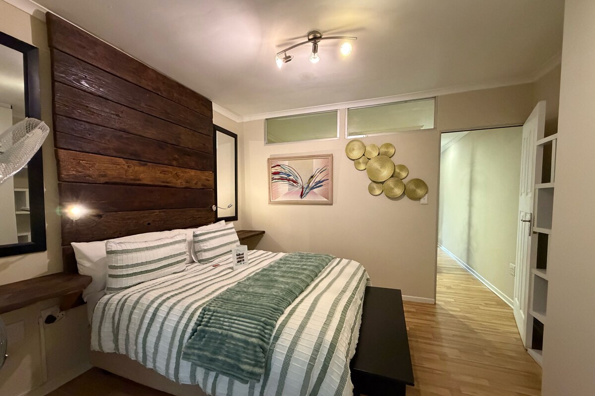 Une chambre à coucher avec un lit, une table de chevet et un ventilateur de plafond.