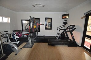 Een huisgymnasium met een loopband, een hometrainer en een krachttrainingapparaat.