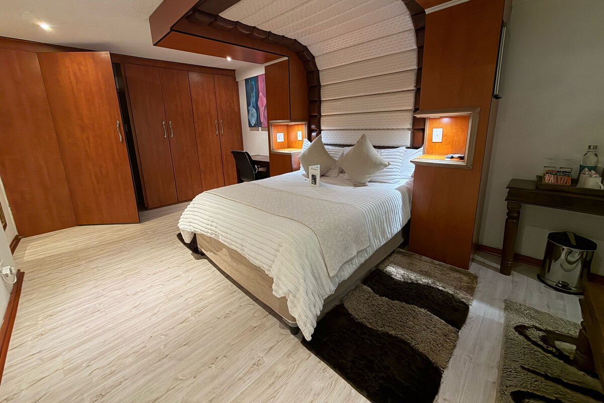 Une chambre à coucher avec un grand lit, une armoire en bois et un bureau avec une lampe.