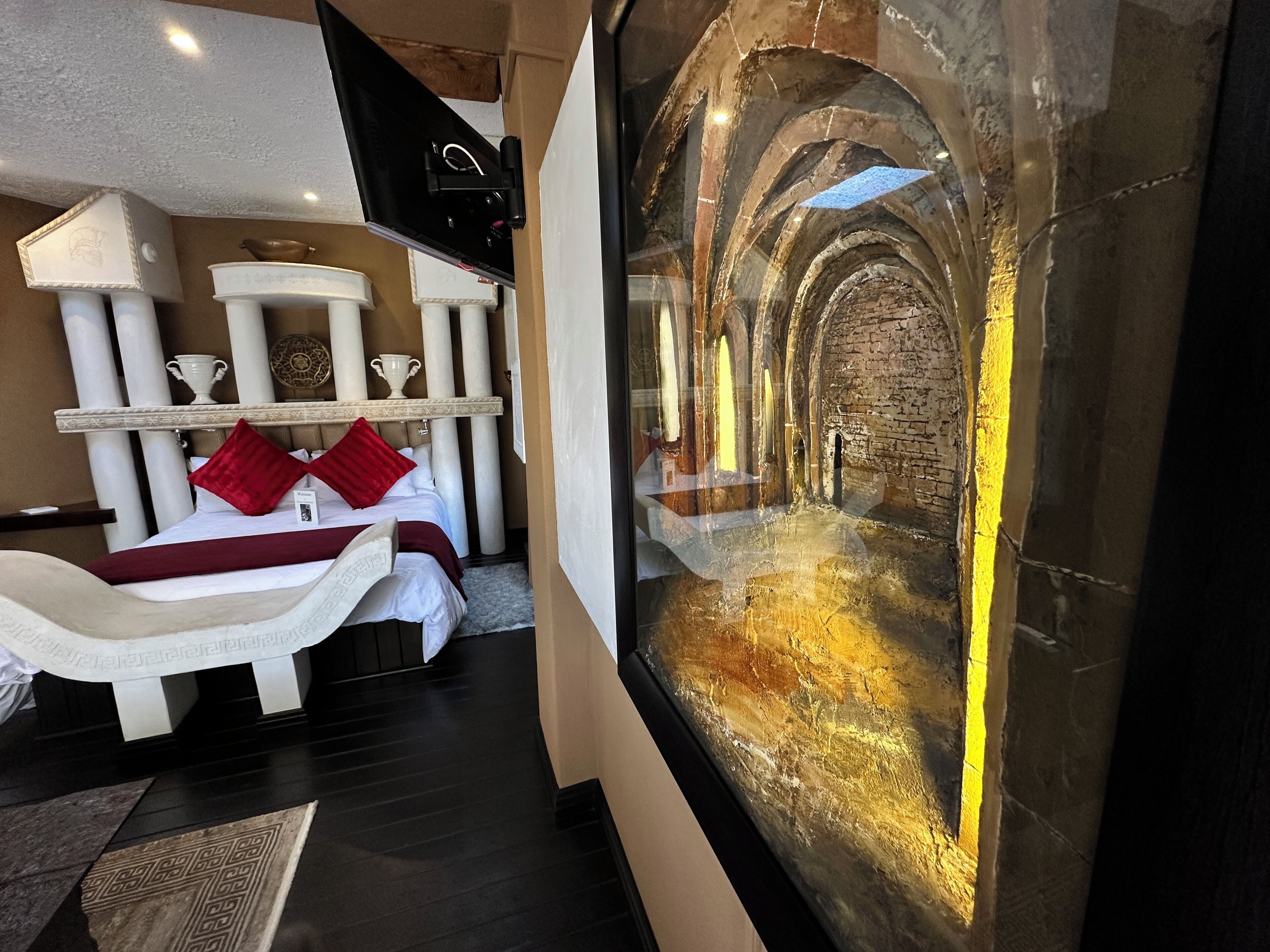 A hotel room with a bed, a large window, and a view of an interior corridor.