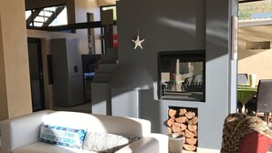A modern living room with a white sofa, a red armchair, and a fireplace. - 11 Escape Views (Cape Town)
