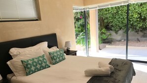 A neatly made bed with white and green pillows, a dark throw blanket, and a folded towel on the side. - 11 Escape Views (Cape Town)