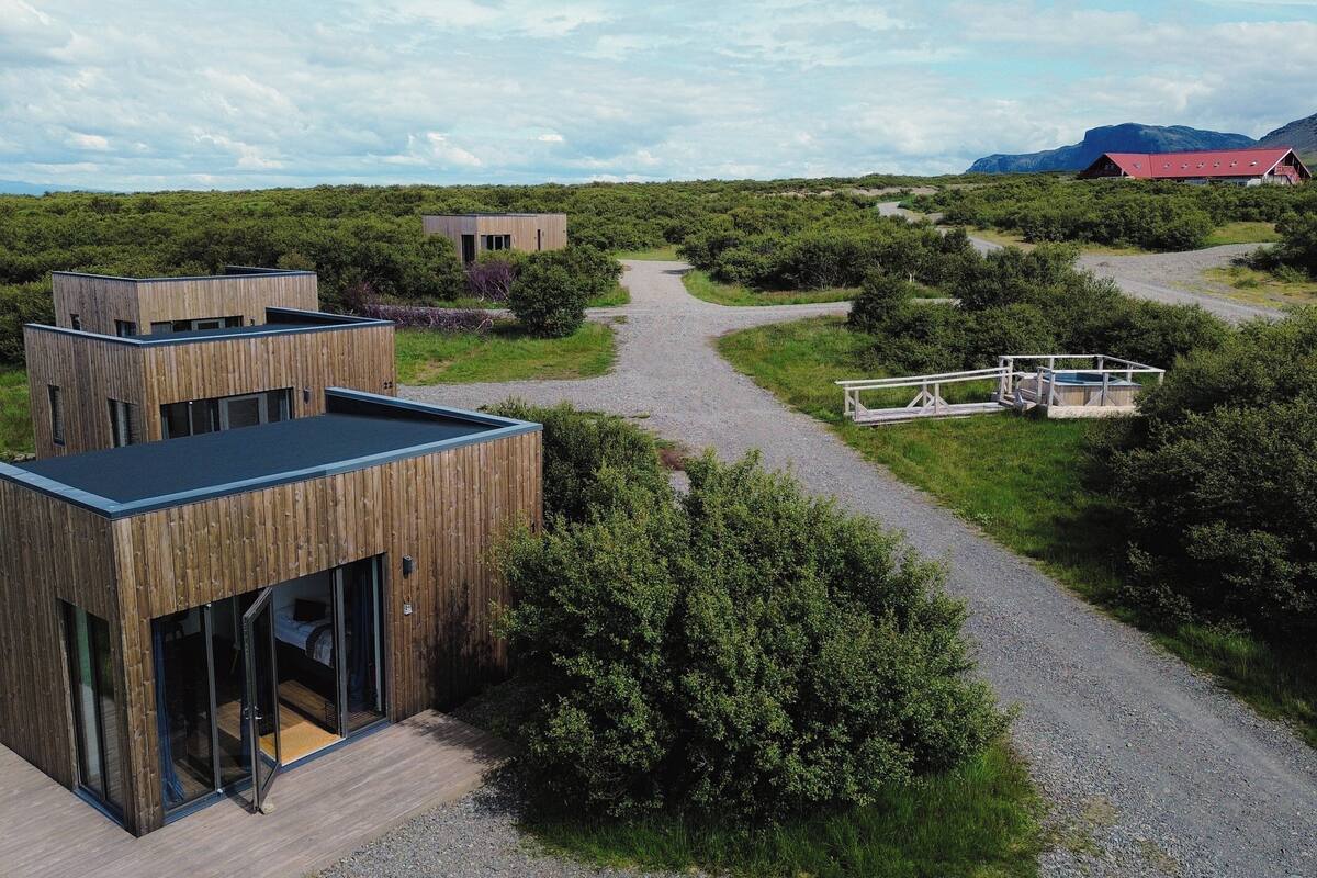 A modern wooden building with a gravel path leading to a wooden deck.