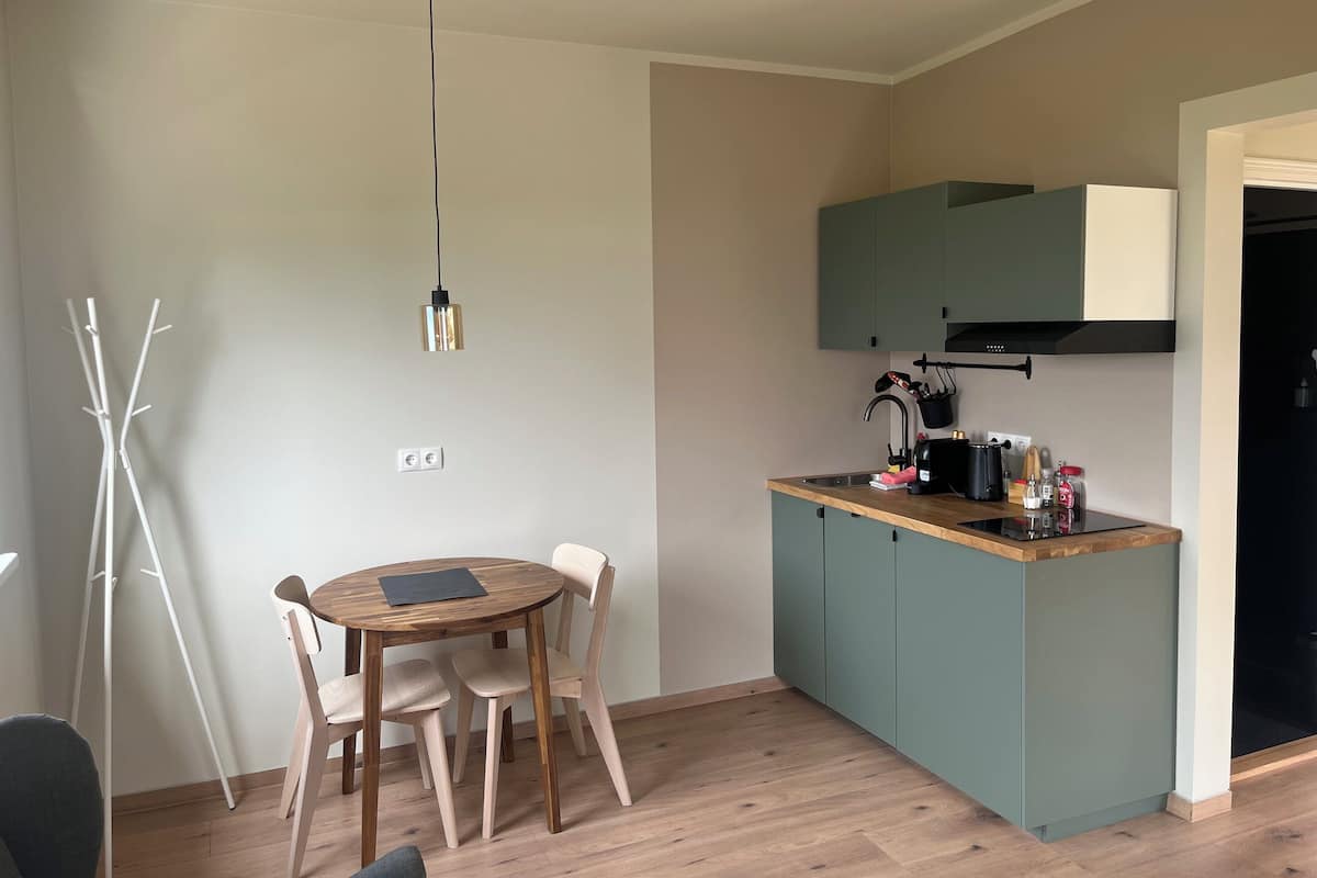 A compact kitchen with a wooden countertop, a built-in stove, and a hanging pot rack.