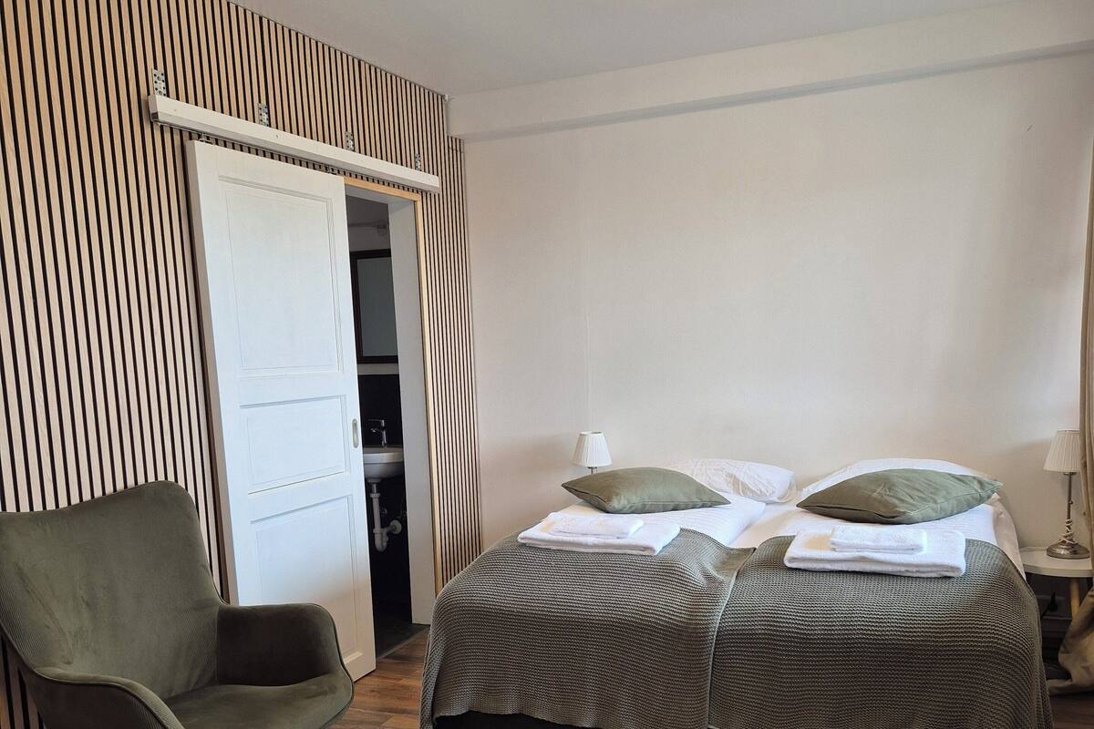 A bedroom with a bed, a chair, a wardrobe, and a ceiling light.