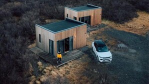 A modern two-story cabin with a flat roof, situated in a remote, open landscape. - Hótel Hafnarfjall (Hvalfjarðarsveit)