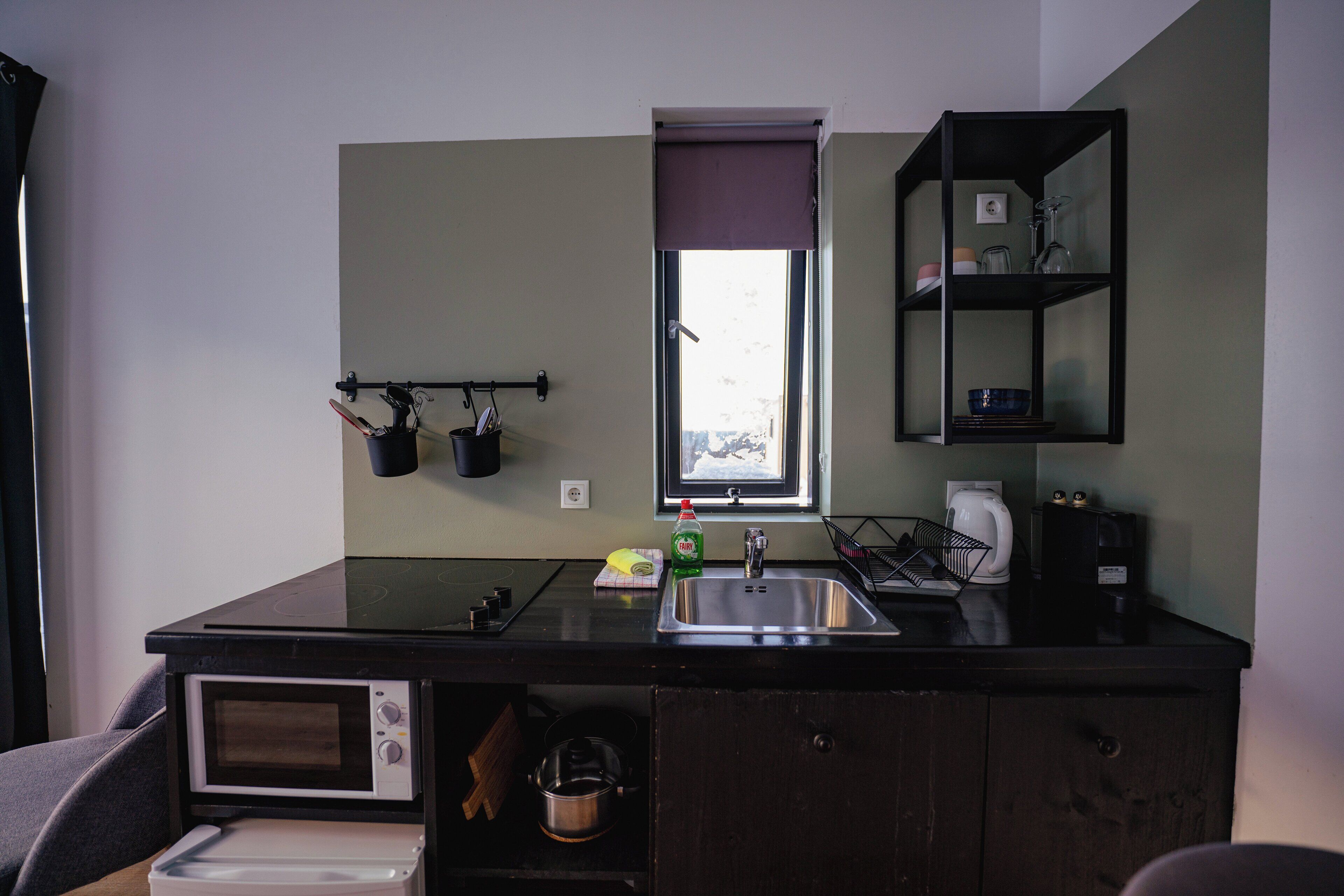 A compact kitchen with a built-in microwave, a sink, and a window above it.