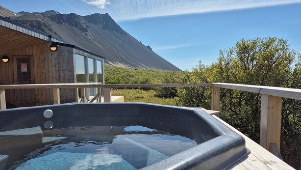 A hot tub on a wooden deck with a mountain view. - Hótel Hafnarfjall (Hvalfjarðarsveit)