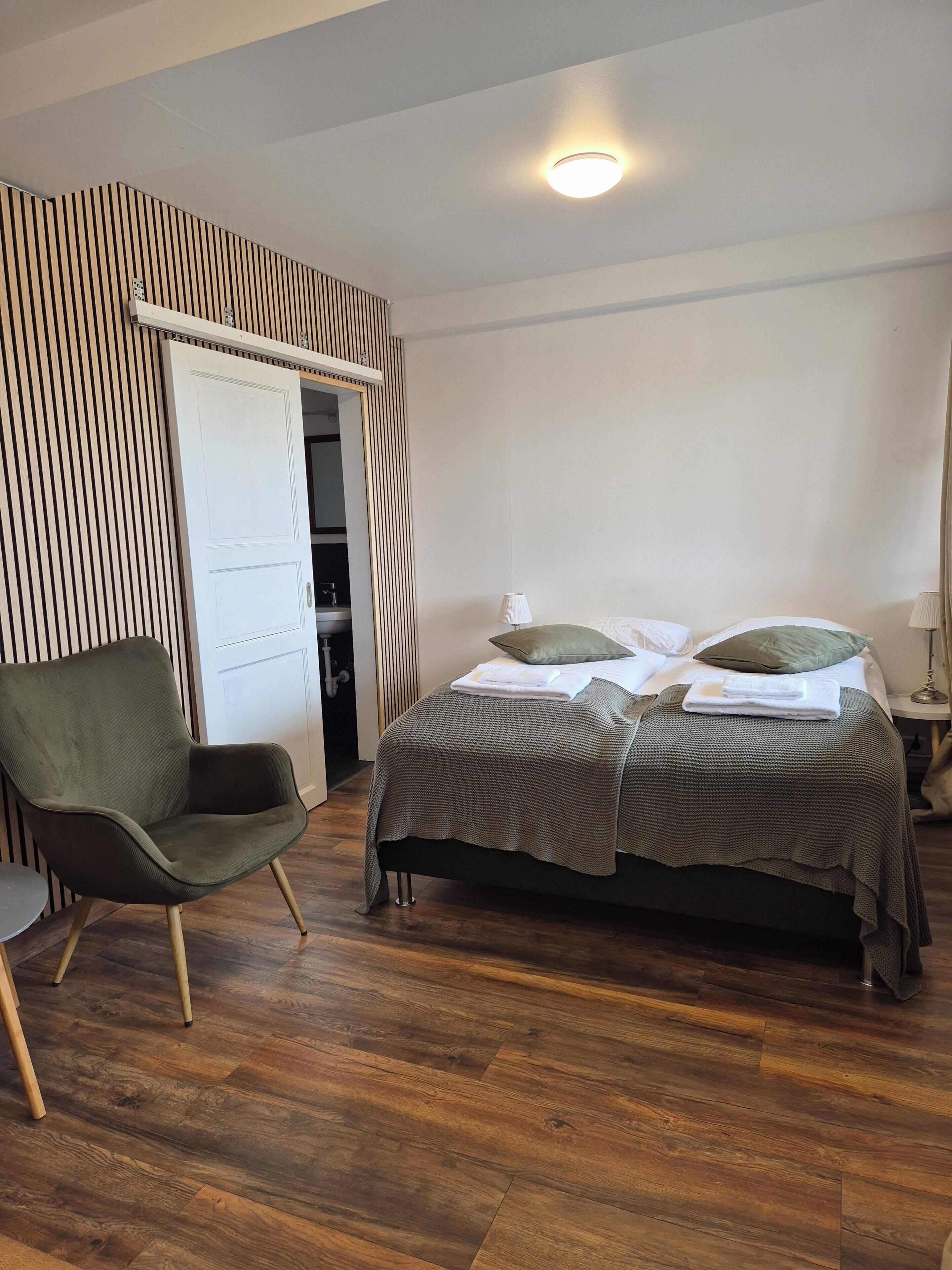 A bedroom with a bed, a chair, a wardrobe, and a ceiling light.