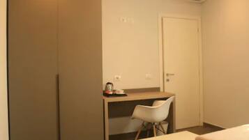 Ein kleines Zimmer mit einem Bett, einem Schreibtisch und einem Stuhl. An einer Seite befindet sich ein Kleiderschrank und auf der anderen eine Tür.