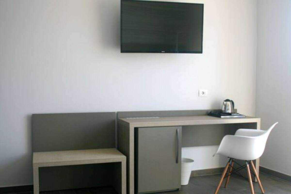 A modern room with a flat-screen TV mounted on the wall, a small desk with a chair, and a bench.