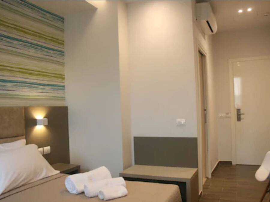 A hotel room with a bed, bedside table, and a wall-mounted light.
