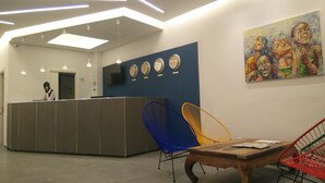 Una zona de recepción con mostrador, un cuadro y varias sillas.
