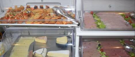 Un bufé con diferentes opciones de comida, incluyendo queso, carnes y verduras.