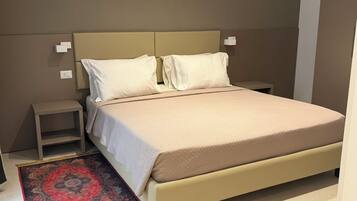 A bedroom with a bed, nightstands, a bedside table, and a patterned rug.