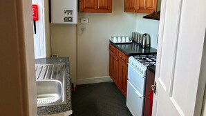 A compact kitchen with wooden cabinets, a white refrigerator, a stove, and a sink.