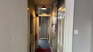 A narrow hallway with a red carpet, white doors, and a red pendant light.