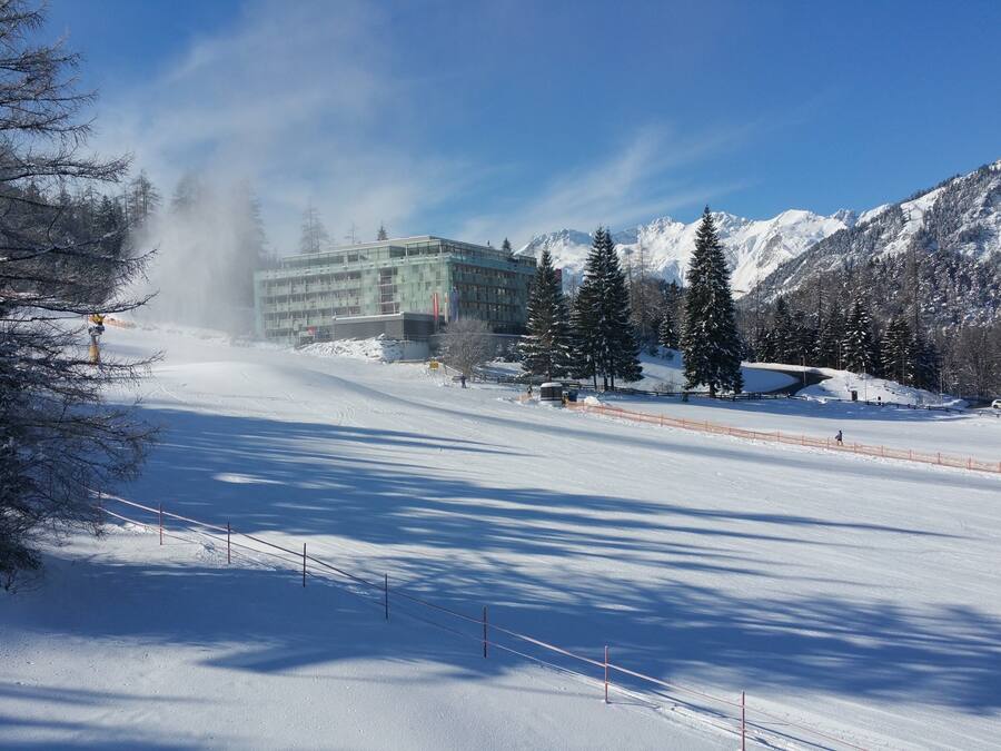 Una pista de esquí cubierta de nieve con un edificio al fondo.