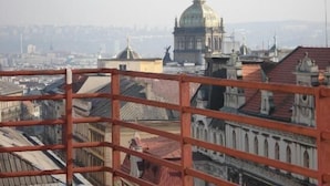 A cityscape with a prominent domed building in the background, viewed from a rooftop with a red railing. - Hotel Legie (Prague)