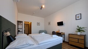 A hotel room with a bed, bedside table, TV, and a desk with a chair. - Hotel Legie (Prague)