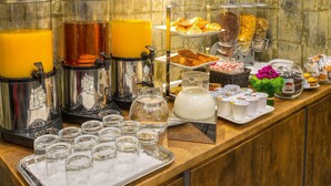 Un buffet proposant une variété de plats et de boissons, notamment des distributeurs de jus et des plateaux de pâtisseries.