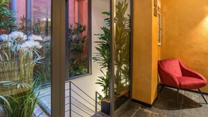 Un intérieur moderne avec un fauteuil rouge, des murs en verre et des plantes d’intérieur.