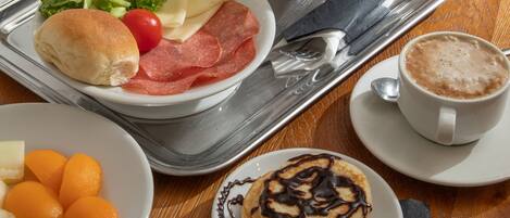 Una mesa de desayuno con diversas opciones de comida, como pastelería, frutas y una tetera.