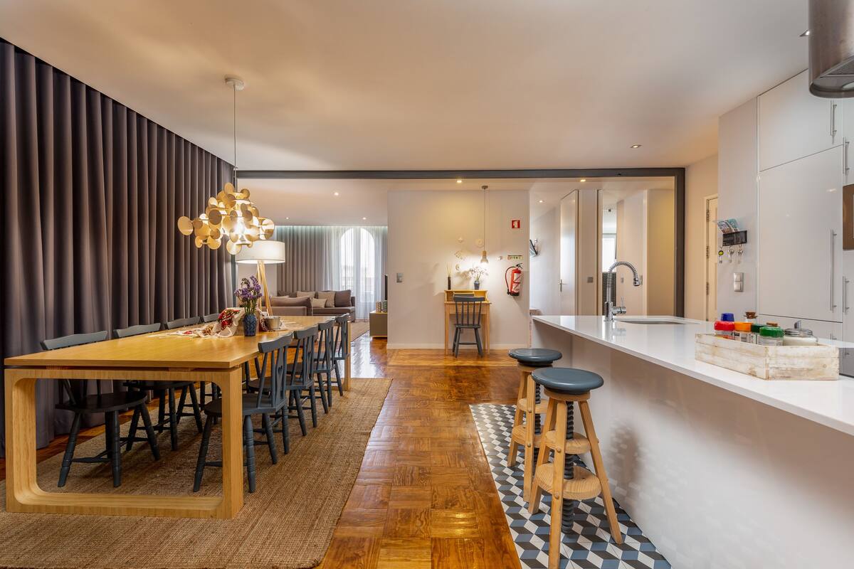 Una cocina moderna con una isla central, una mesa de comedor de madera y taburetes de bar.
