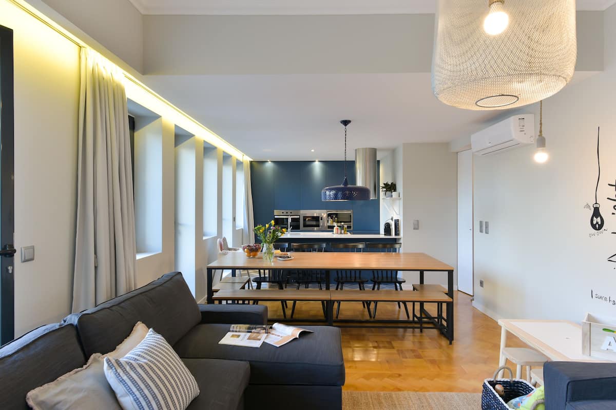 Una sala de estar moderna con sofá, mesa de comedor y cocina al fondo.
