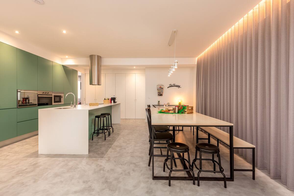 Una cocina moderna con una isla central, taburetes de bar y una mesa de comedor con sillas.
