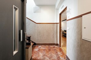 Un pasillo con suelo de diseño herringbone, un marco de puerta de madera y una pared blanca con un cartel.
