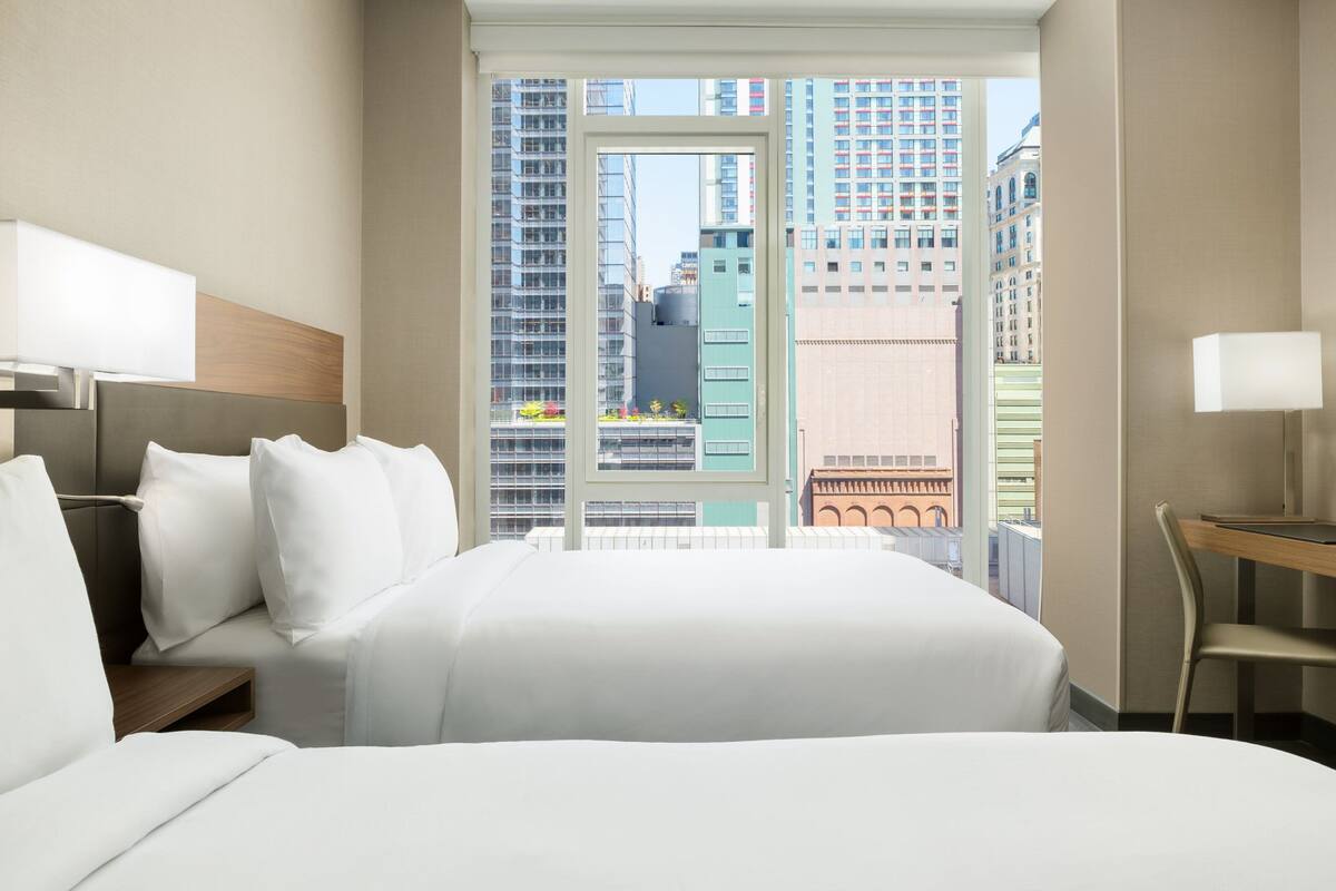 Een hotelkamer met een groot bed, een bureau en een raam met uitzicht op de stad.