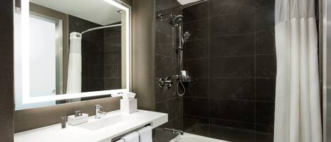 A modern bathroom with a white sink, mirror, and bathtub.