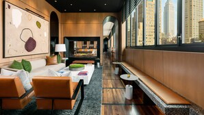 Un hall d’hôtel moderne avec un long banc, un espace salon et une vue sur l’Empire State Building.