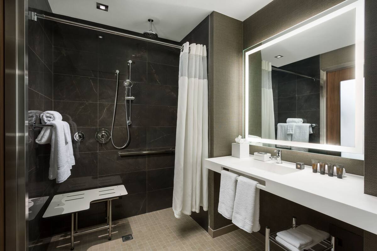 Een moderne badkamer met een douche met glazen wand, een grote spiegel en een wit wastafelmeubel.