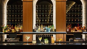 Un espace bar avec de nombreuses étagères remplies de bouteilles d’alcool, une caisse enregistreuse et plusieurs verres remplis de boissons.