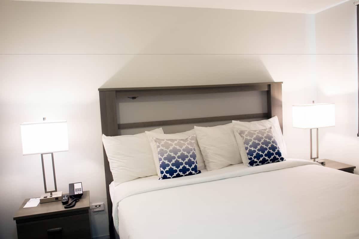 A hotel room with a bed, bedside lamps, a phone, and a nightstand.