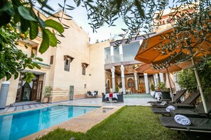 Una piscina al aire libre, sombrillas, sillones reclinables de piscina