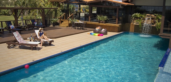 A swimming pool with lounge chairs and a deck area. - Village Praia do Rosa (Imbituba)