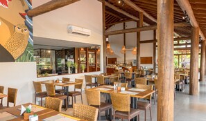 A restaurant with wooden beams, wicker chairs, and tables. - Village Praia do Rosa (Imbituba)