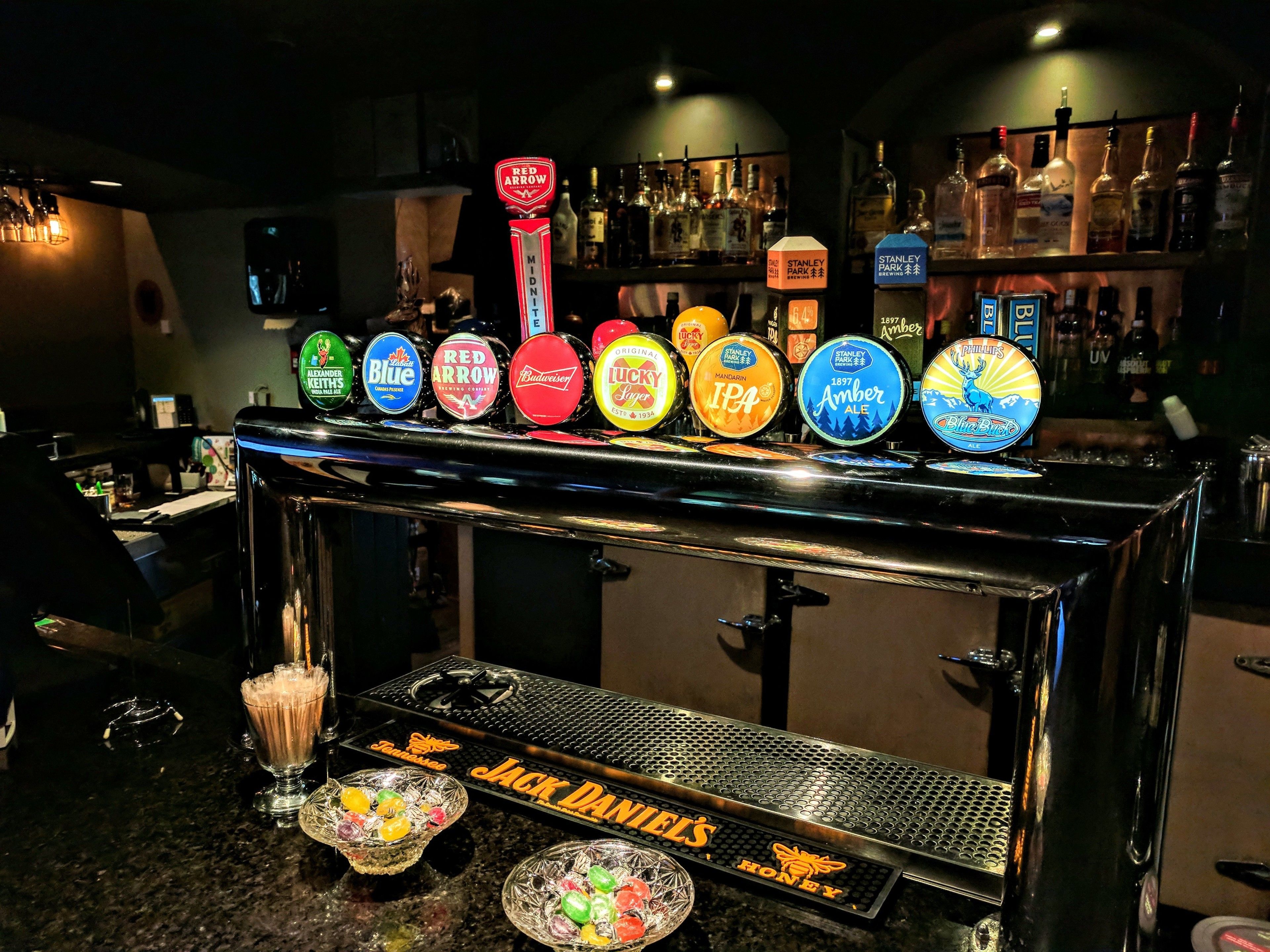 A bar with a variety of beer taps and a bottle of Jack Daniel's Honey whiskey.