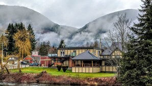 A lakeside building with a dock, surrounded by mountains and trees. - Riverside Inn (Lake Cowichan)