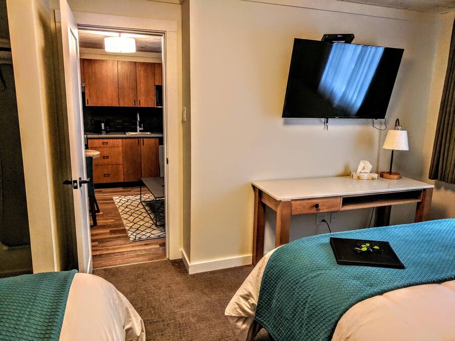 A hotel room with a bed, a desk, a TV, and a kitchenette.