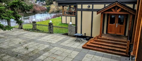 A house with a wooden deck, a pond, and a view of a forested area.