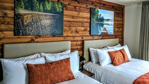 A hotel room with two beds, wooden paneling on the walls, and two large landscape paintings. - Riverside Inn (Lake Cowichan)