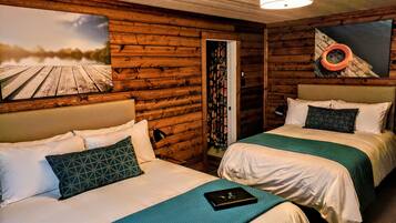 A cabin-style room with two beds, wooden walls, a painting of a boat, and a ceiling light.